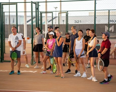 Group of adult tennis players gathered on court during a training session