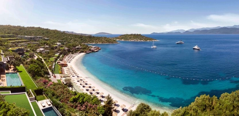 Bodrum beach with turquoise water, sun loungers, and a scenic coastline.