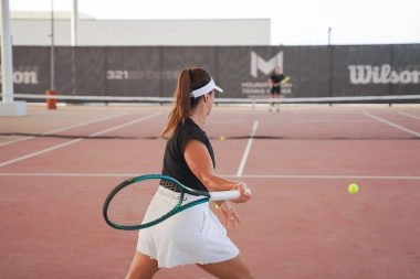 Female tennis player hitting a forehand during practice on a covered court