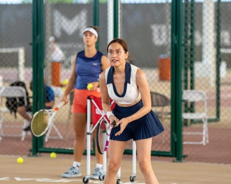 Two female tennis players preparing for a drill on an indoor court