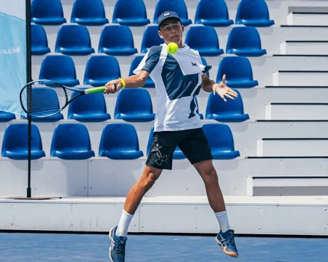 Joueur de tennis frappant un coup droit lors d'un match dans un stade extérieur avec des sièges bleus