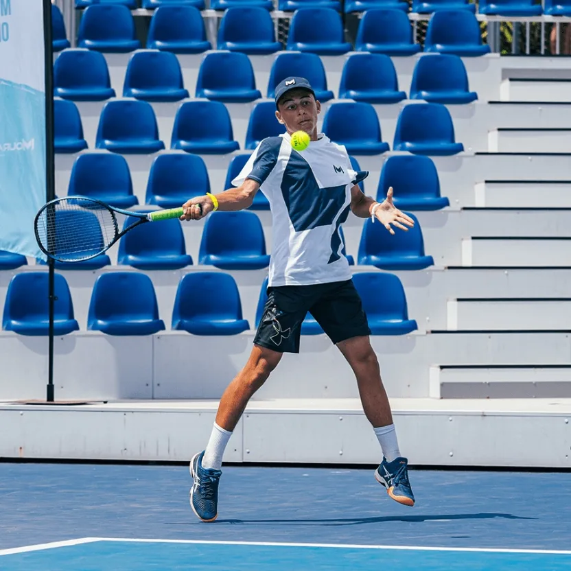 Joueur de tennis frappant un coup droit lors d'un match dans un stade extérieur avec des sièges bleus