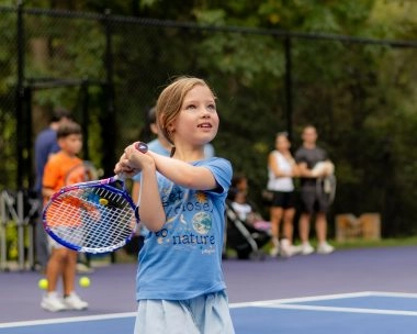 A young girl playing tennis on an outdoor court at Mouratoglou Academy Atlanta.