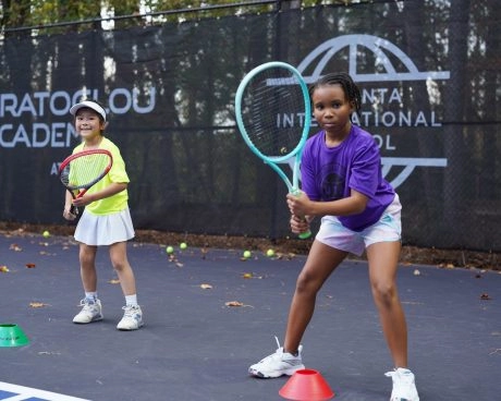 Deux jeunes joueurs de tennis s'entraînant avec leur coach sur le court de la Mouratoglou Academy Atlanta.