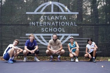 Federico with Tennis & School students seated in front of Mouratoglou windbreakers at Mouratoglou Academy Atlanta