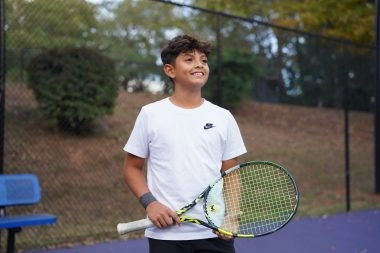 Jeune joueur de tennis souriant tenant une raquette à l'Académie Mouratoglou d'Atlanta