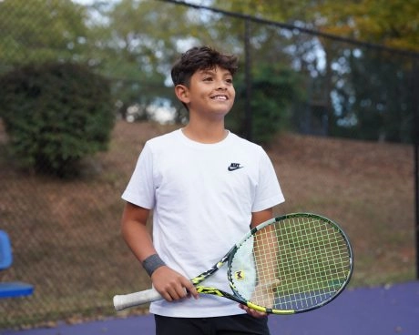 Jeune joueur de tennis souriant tenant une raquette à l'Académie Mouratoglou d'Atlanta