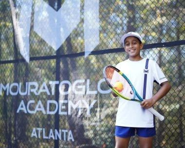 Jeune joueur de tennis souriant tenant une raquette à l'Académie Mouratoglou d'Atlanta.