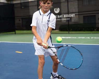 Child playing tennis on an outdoor court at Horseshoe Bay, Mouratoglou Tennis Center.