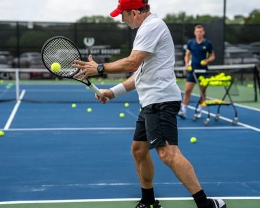 A man hitting a backhand during a private tennis lesson with a coach at Mouratoglou Tennis Center Horseshoe Bay.