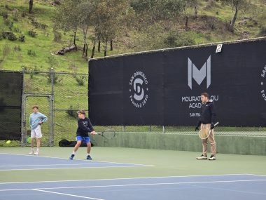 Tennis coach training two boys on an outdoor court at Mouratoglou Academy San Francisco.