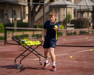 Tennis coach throwing a ball on a clay court at Mouratoglou Tennis Center Horseshoe Bay.