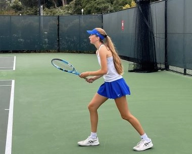 A young woman preparing to hit a tennis shot on an outdoor court at Mouratoglou Academy San Francisco.