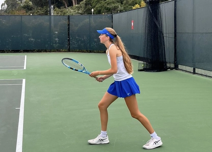 A young woman preparing to hit a tennis shot on an outdoor court at Mouratoglou Academy San Francisco.