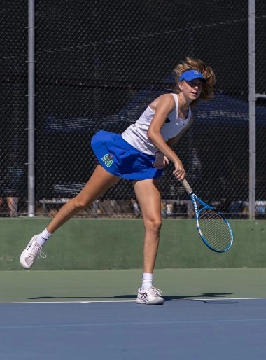 Female tennis player serving on an outdoor hard court