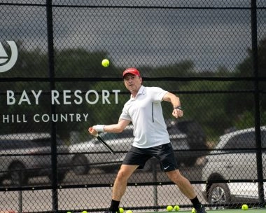 Un adulte frappe un coup droit lors d’une leçon privée de tennis avec un coach sur un court extérieur au Mouratoglou Tennis Center à Horseshoe Bay.