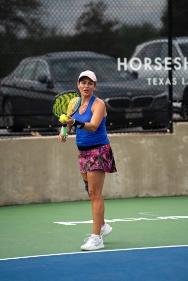 Une femme se prépare à effectuer un service sur un court extérieur au Mouratoglou Tennis Center à Horseshoe Bay.