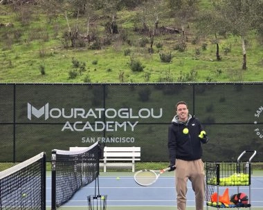 Tennis coach feeding tennis balls to players on an outdoor court at Mouratoglou Academy San Francisco.