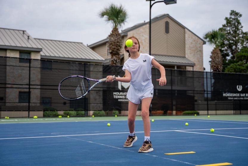 Young girl hitting a tennis ball during practice at Horseshoe Bay, Mouratoglou Tennis Center.