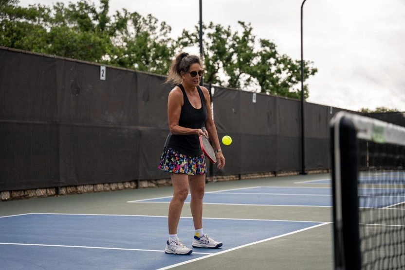 A woman playing pickleball on an outdoor court at Mouratoglou Tennis Center Horseshoe Bay.