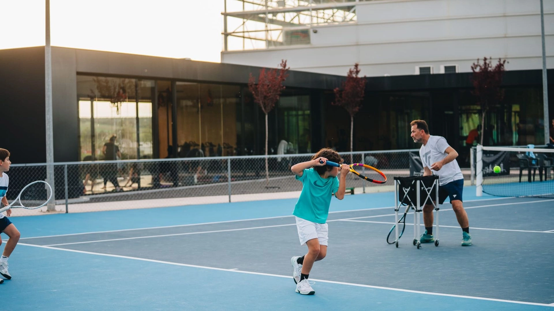 Children training with a coach on blue tennis courts at Mouratoglou Tennis Center Calatrava