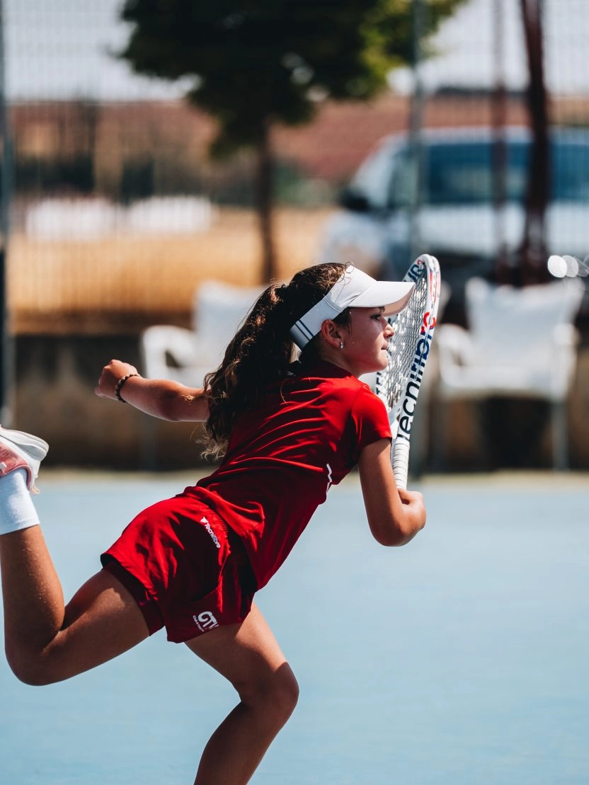 Ragazza che tira un colpo di tennis su un campo all'aperto del Mouratoglou Tennis Center di Calatrava.