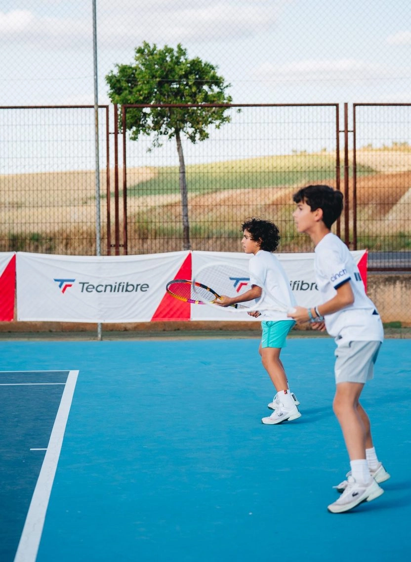Two children playing tennis together on an outdoor court at Mouratoglou Tennis Center Calatrava.
