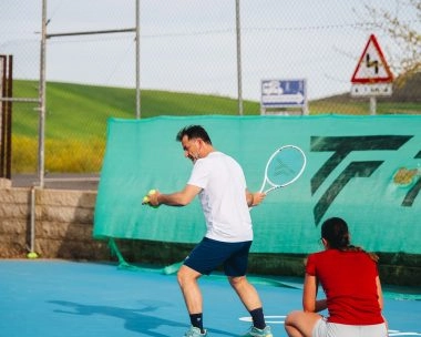 Tennis coach training a player on an outdoor hard court at Mouratoglou Tennis Center Calatrava