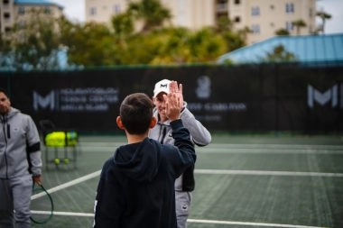 Tennis coach giving a high five to a young player on court at Mouratoglou Tennis Center Amelia Island.