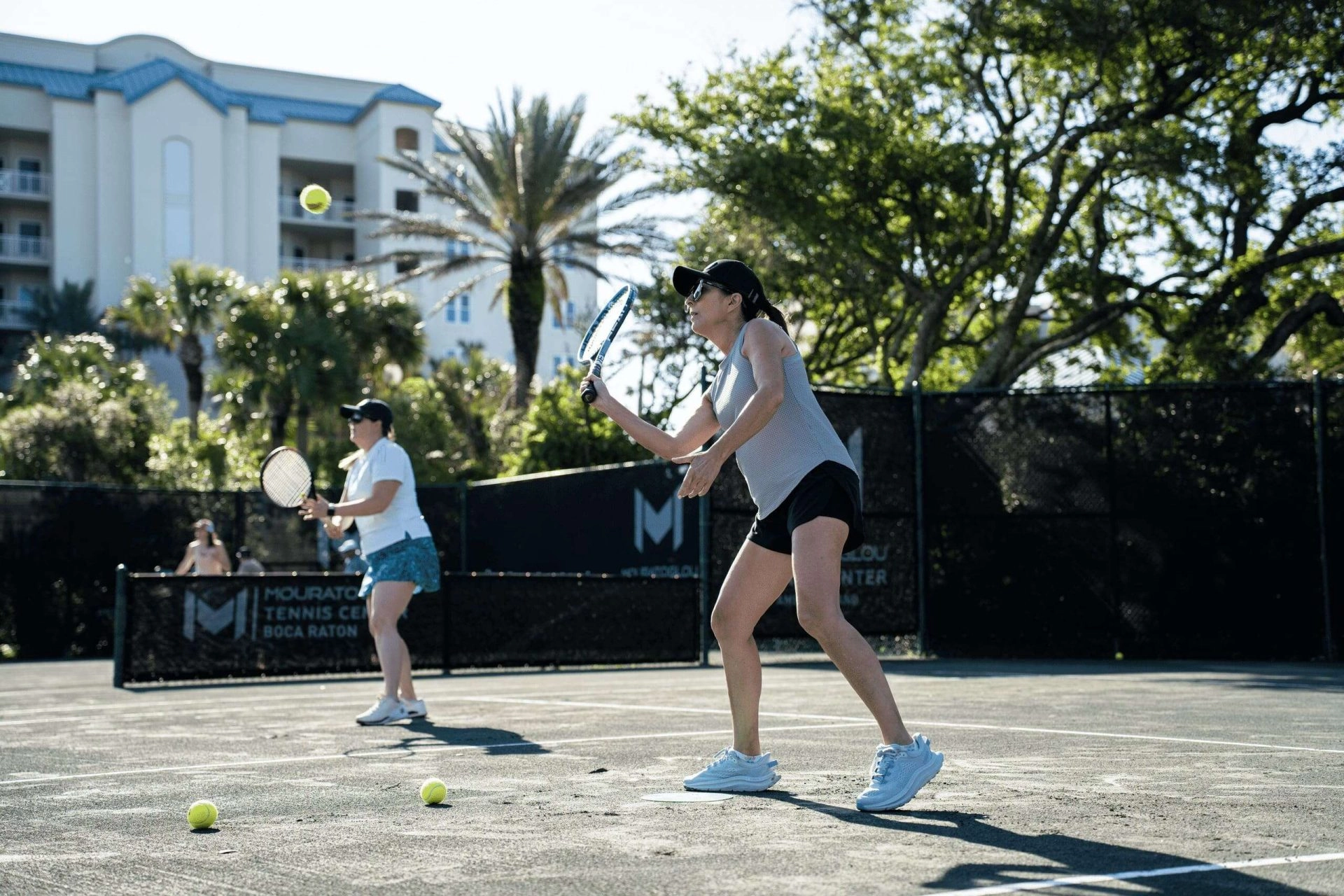 Group of adult tennis players participating in an outdoor tennis camp session at Mouratoglou Tennis Center Boca Raton.