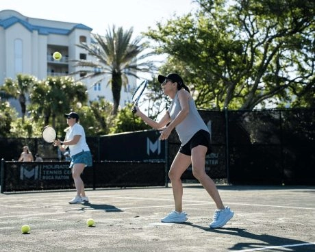 Group of adult tennis players participating in an outdoor tennis camp session at Mouratoglou Tennis Center Boca Raton.