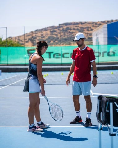 Tennis coach giving advice to a player during training at Mouratoglou Tennis Center Calatrava on blue outdoor court
