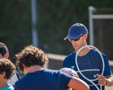 Group private tennis lesson with children and a coach on a sunny outdoor hard court at Mouratoglou Tennis Center Calatrava