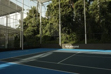 Semi-indoor covered hard tennis court at Mouratoglou Tennis Center Bali with surrounding tropical foliage.