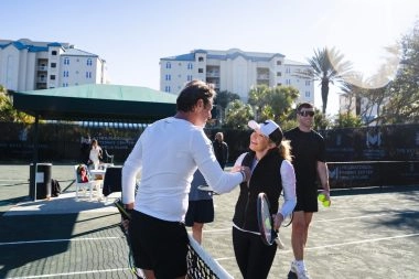 Patrick Mouratoglou greeting a female player on the tennis courts at Mouratoglou Tennis Center Amelia Island.
