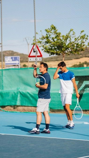Tennis coach giving instructions to a player on a blue hard court at Mouratoglou Tennis Center Calatrava