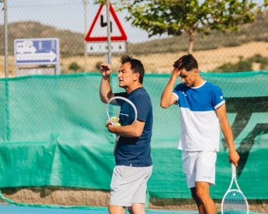 Tennis coach giving instructions to a player on a blue hard court at Mouratoglou Tennis Center Calatrava