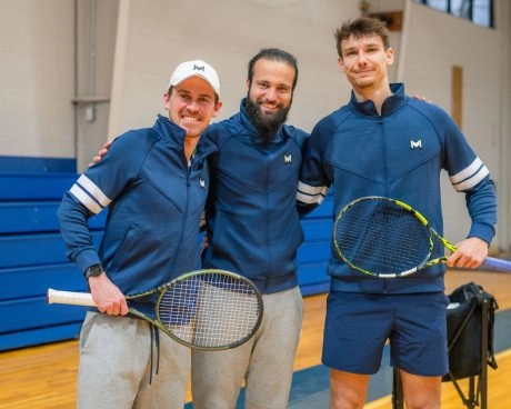 Tennis coaches and players standing together on a court at Mouratoglou Academy Atlanta with tennis rackets.