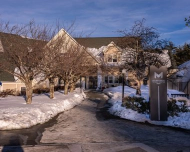Exterior view of Mouratoglou Tennis Center Boston with branded totem in the snow, Massachusetts