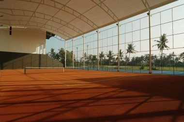 Semi-indoor clay tennis court at Mouratoglou Tennis Center Bali surrounded by tropical scenery