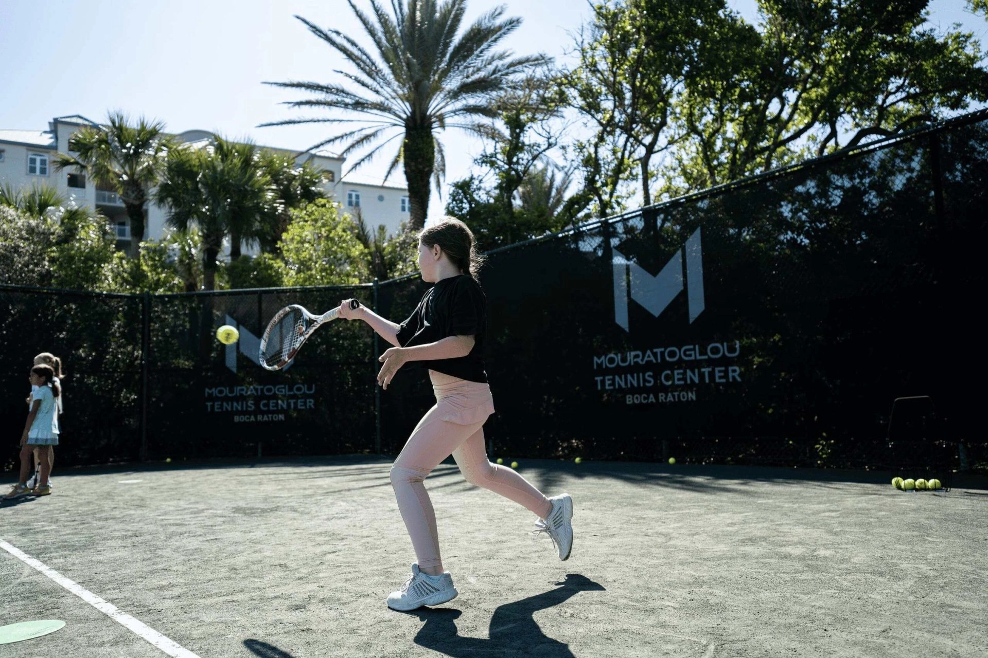 Junior tennis players participating in a youth tennis camp at Mouratoglou Tennis Center Boca Raton.