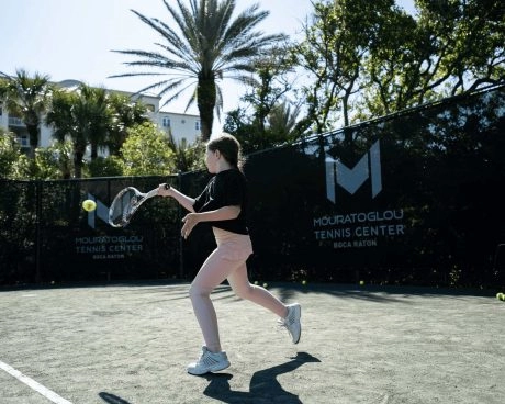 Junior tennis players participating in a youth tennis camp at Mouratoglou Tennis Center Boca Raton.