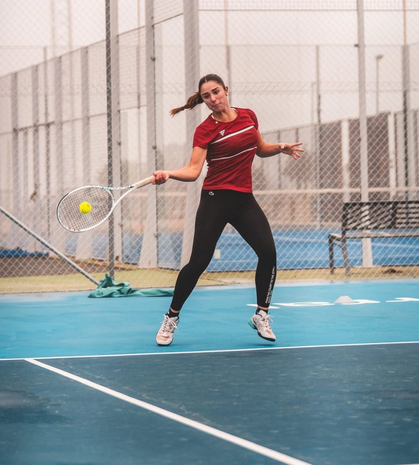 Woman striking a tennis ball on an outdoor court at Mouratoglou Tennis Center Calatrava.