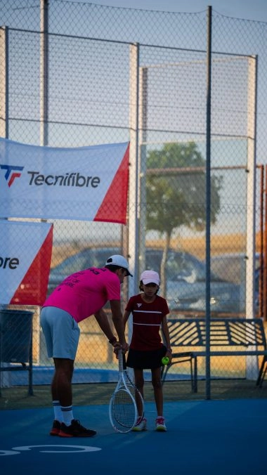 Tennis coach teaching a young player on a blue hard court at Mouratoglou Tennis Center Calatrava