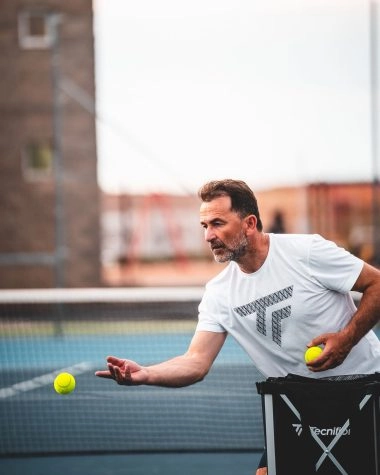 Tennis coach feeding a ball during a private lesson on a sunny outdoor hard court at Mouratoglou Tennis Center Calatrava