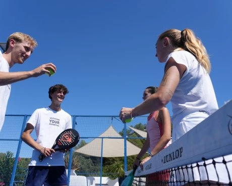 Four padel players gathered at the net on an outdoor padel court