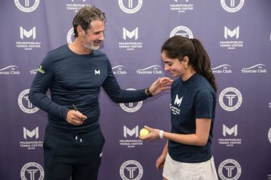 Patrick Mouratoglou signing tennis ball at Mouratoglou Tennis Center Boston