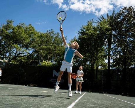 Young junior tennis players training together on an outdoor court at Mouratoglou Tennis Center Boca Raton.