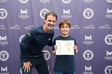 Patrick posing with a young player in front of the Mouratoglou photo wall at Mouratoglou Tennis Center Boston