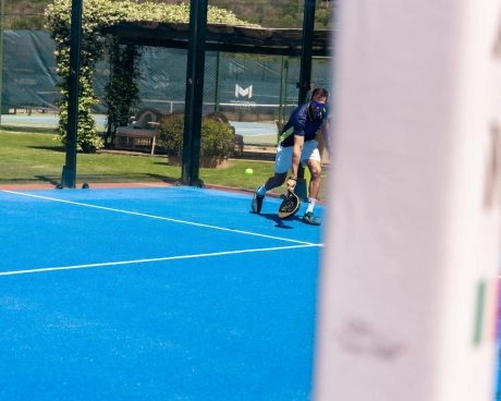 Padel player returning a shot at Mouratoglou Tennis Center Sardinia.